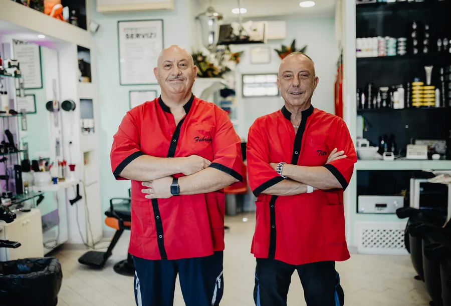 Tito e Fabrizio in negozio, in piedi a braccia conserte