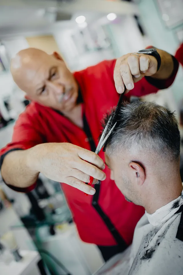 Un barbiere taglia i capelli con forbici e pettine