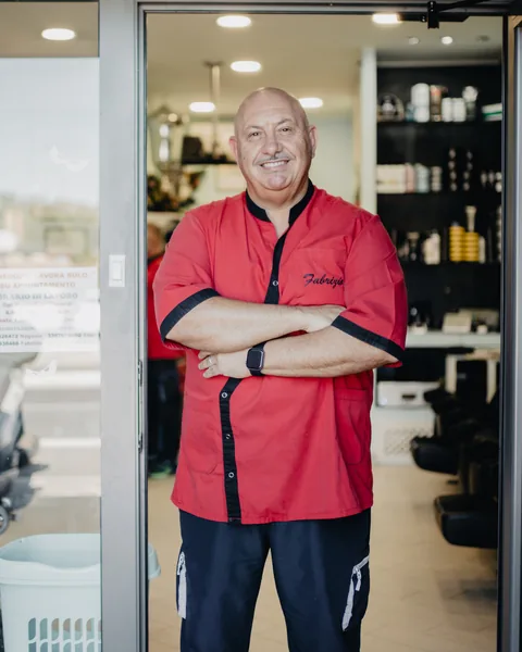 Fabrizio sulla porta della bottega, a braccia conserte